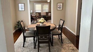 A dining area with a round table, four chairs, and a vase of flowers. - Pet-Friendly 2BR | 2 Baths · Near Motor Speedway (Concord)