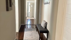 A hallway with a bench, a patterned rug, and a door with a sign. - Pet-Friendly 2BR | 2 Baths · Near Motor Speedway (Concord)
