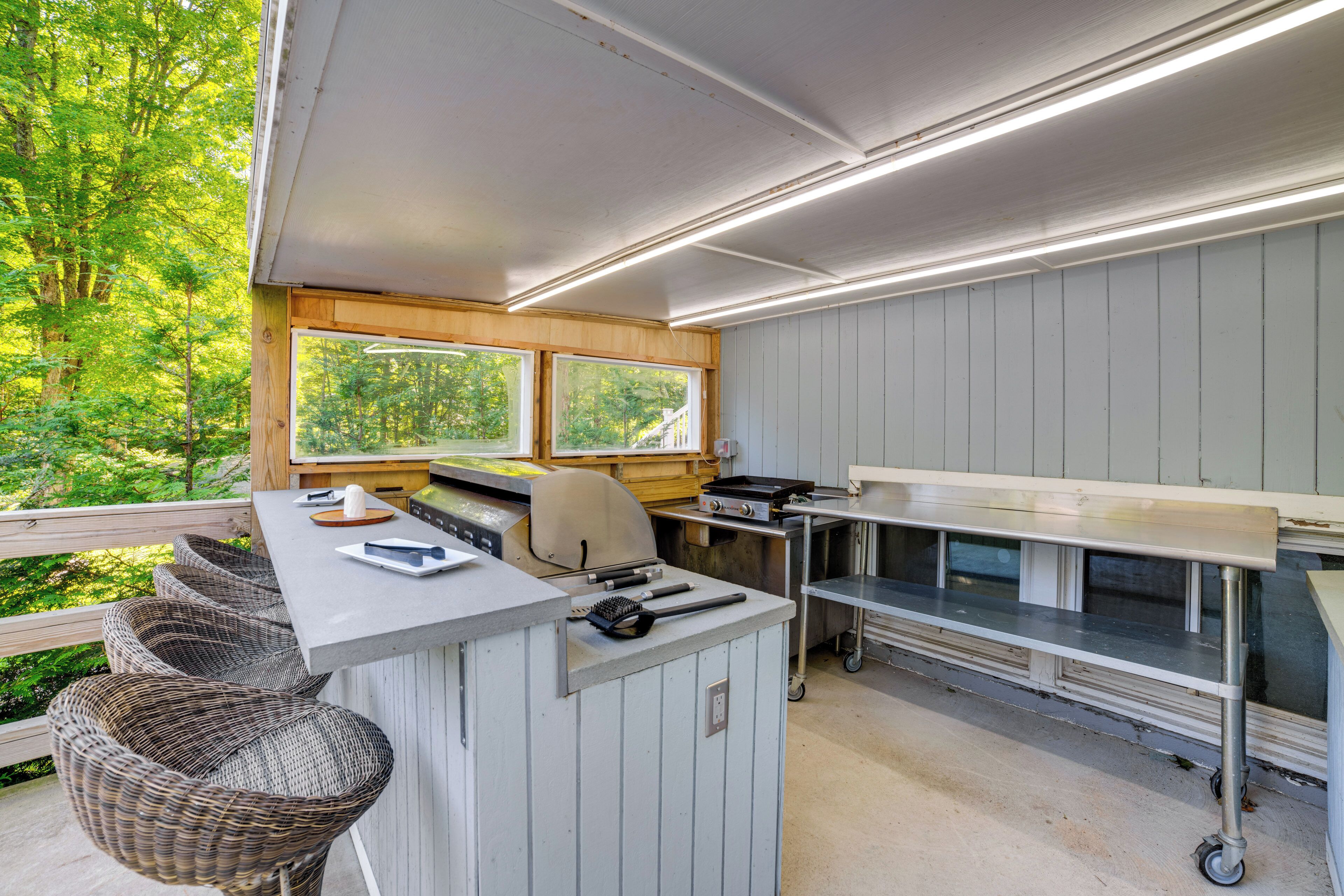 Une cuisine dotée d’un comptoir en bois, d’un barbecue et offrant une vue sur l’extérieur.