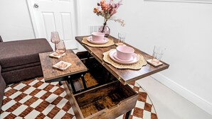 Ein Esstisch mit rosa Tellern und Gläsern, eine Vase mit Blumen und ein karierter Boden.