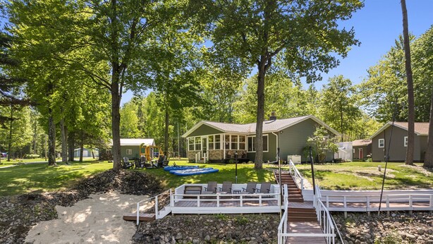 A backyard with a wooden deck, a small pool, and a house with a large window overlooking the yard. - Lakeside Lodge - Game Cave, Golf Greens! Sleeps 17 (Gladwin)