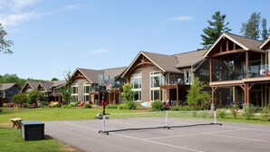 Een wooncomplex met meerdere huizen, een tennisbaan en een basketbalveld.