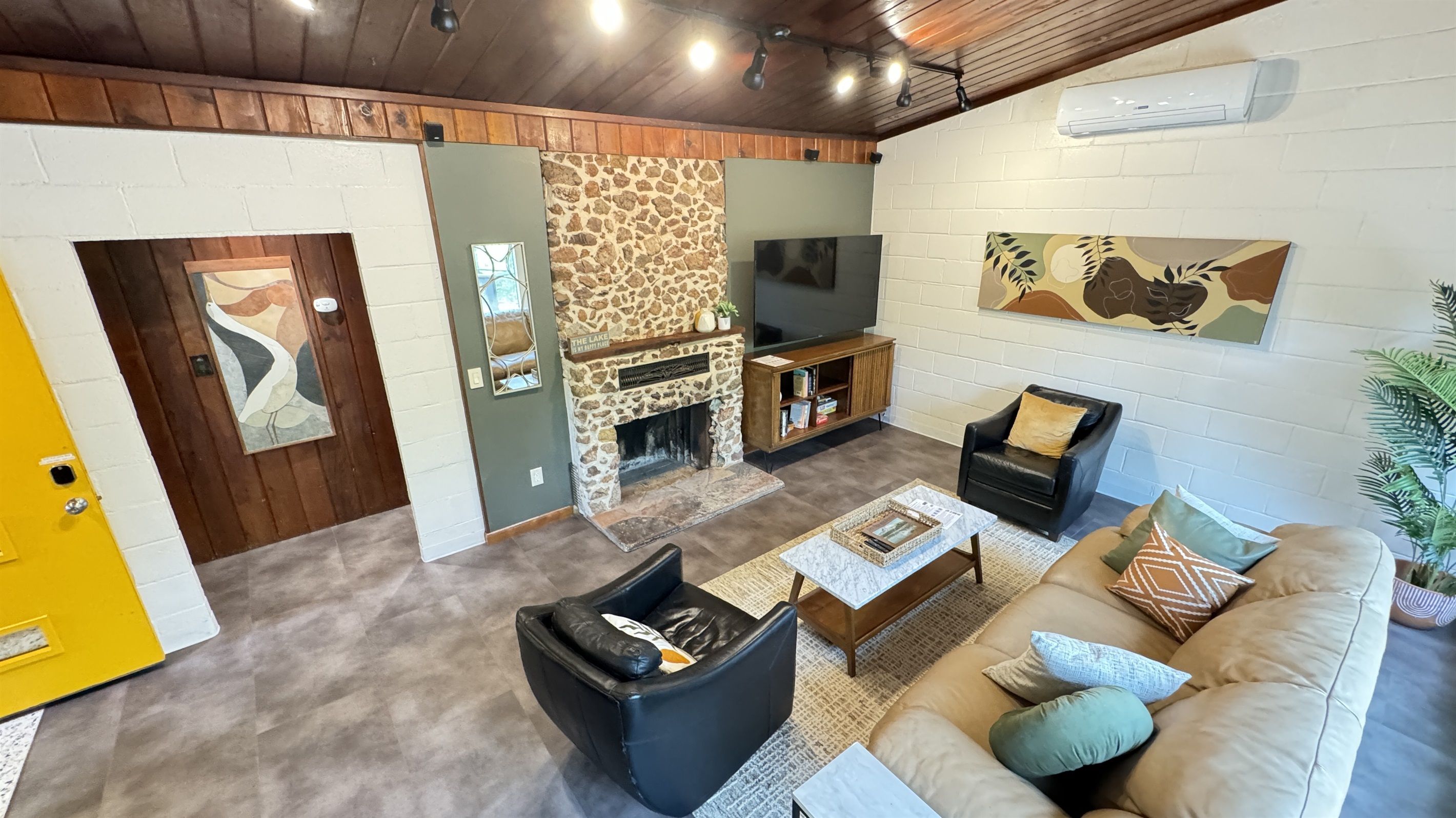 Una sala de estar con chimenea de piedra, un televisor de pantalla plana, un sofá y una mesa de centro.