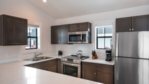 Una cocina moderna con armarios de madera oscura, electrodomésticos de acero inoxidable y una encimera de mármol blanco.