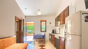 A compact kitchen with a dining table, a sofa, and a refrigerator.