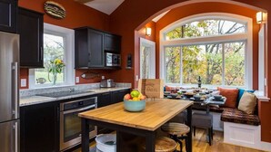Una cocina con armarios oscuros, una mesa de madera y una ventana con vistas a un jardín.