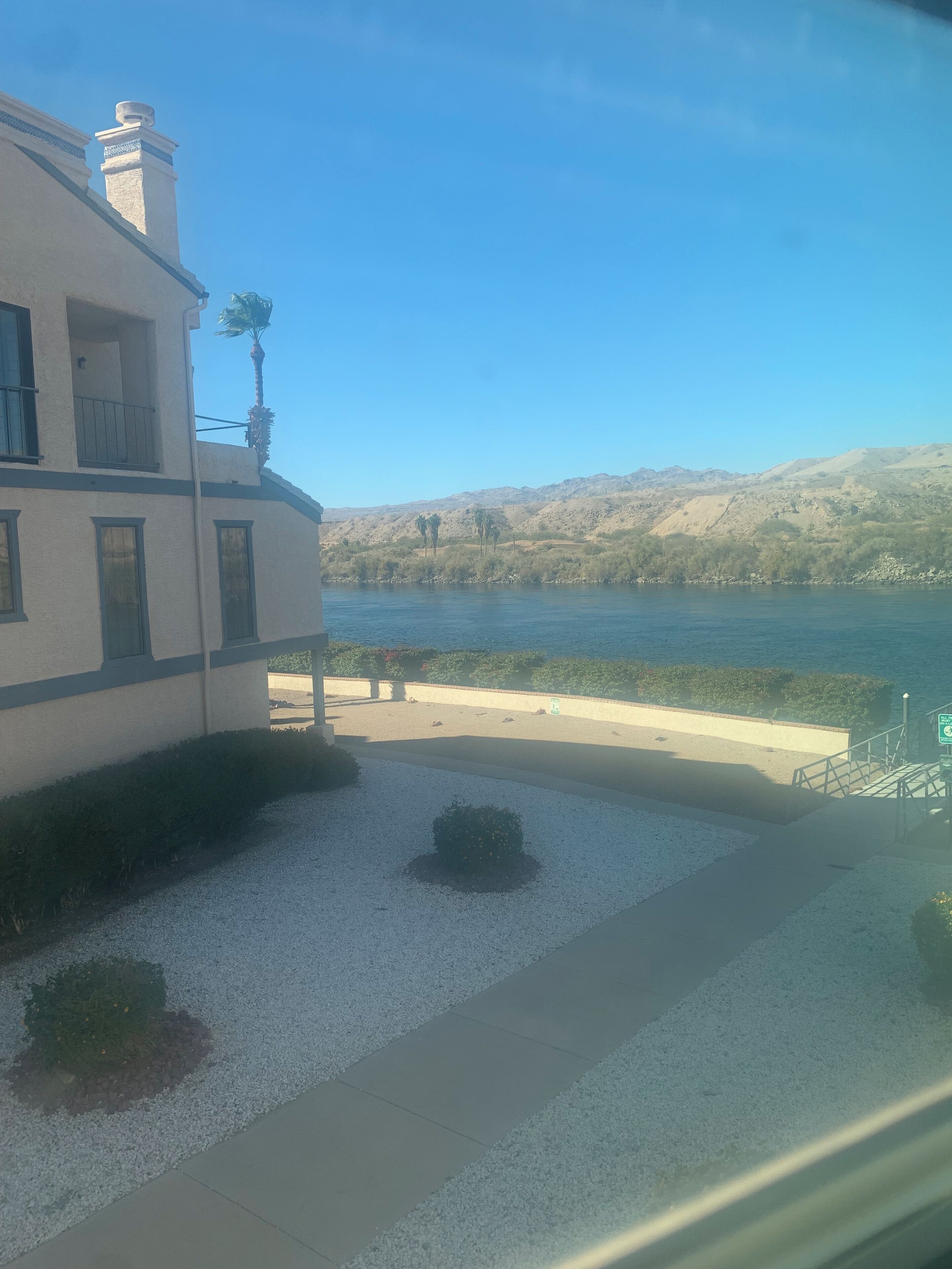 A building with a balcony overlooking a body of water and hills.