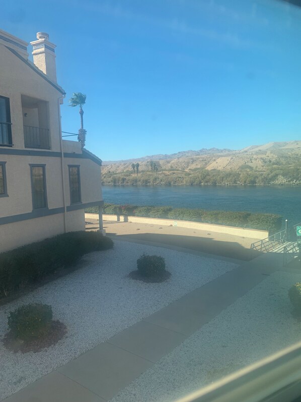 A building with a balcony overlooking a body of water and hills.