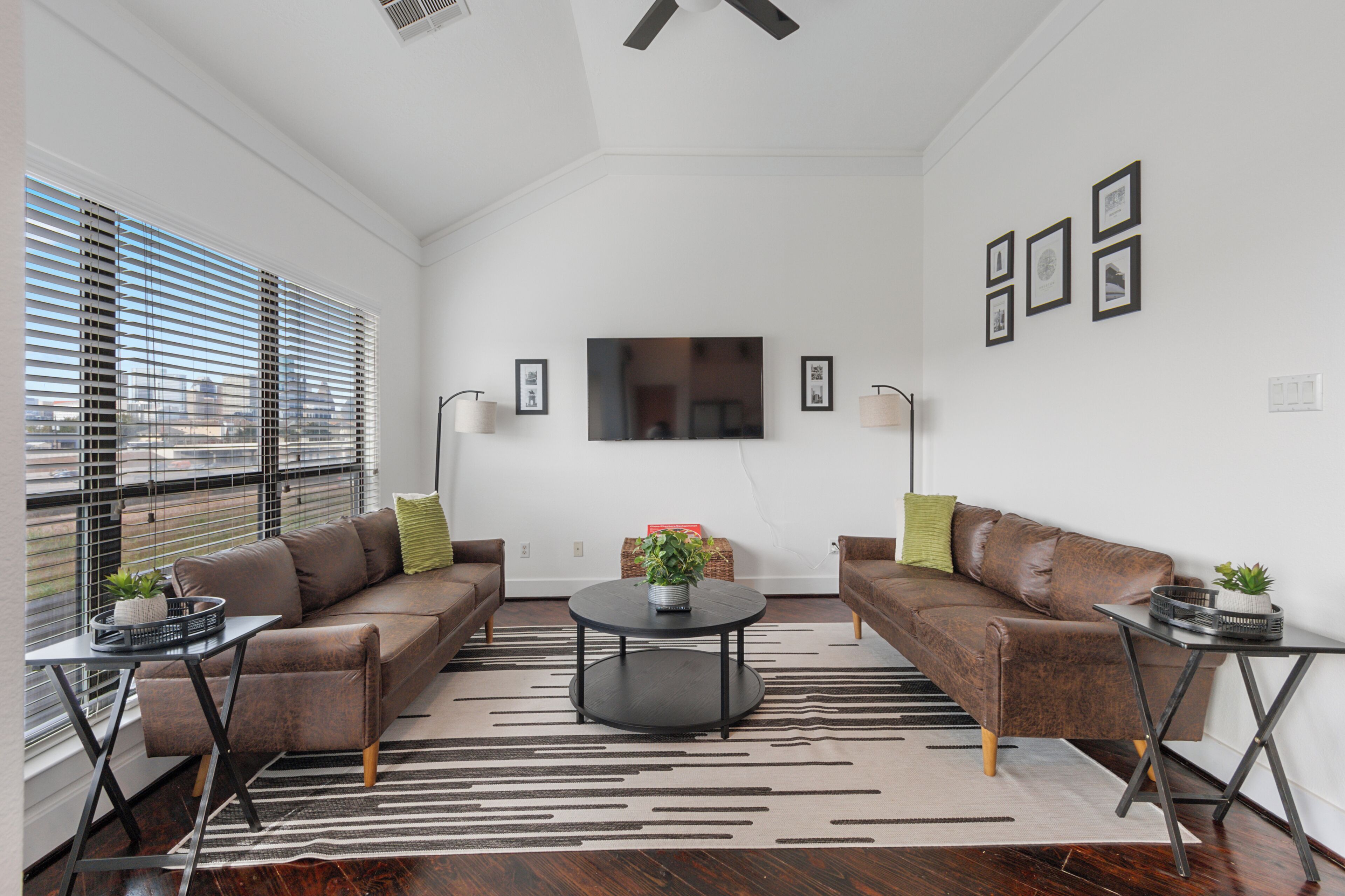A modern living room with two sofas, a coffee table, and a TV mounted on the wall.