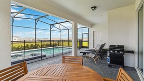 Una terrassa coberta amb vista a una piscina, un barbacoa i seients exteriors.