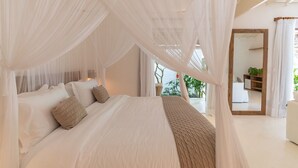 A bedroom with a canopy bed, a large mirror, and a view of the outdoors.