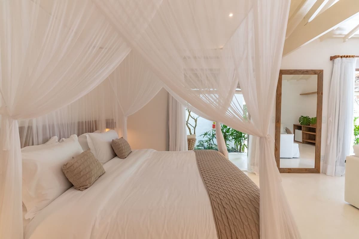 Ein Schlafzimmer mit Himmelsbett, großem Spiegel und Blick ins Freie.