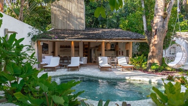 A poolside area with lounge chairs and a covered seating area.
