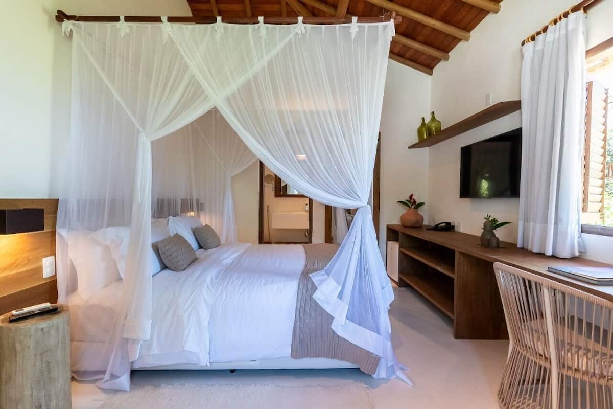 Ein Schlafzimmer mit Himmelbett, Schreibtisch und Fernseher.