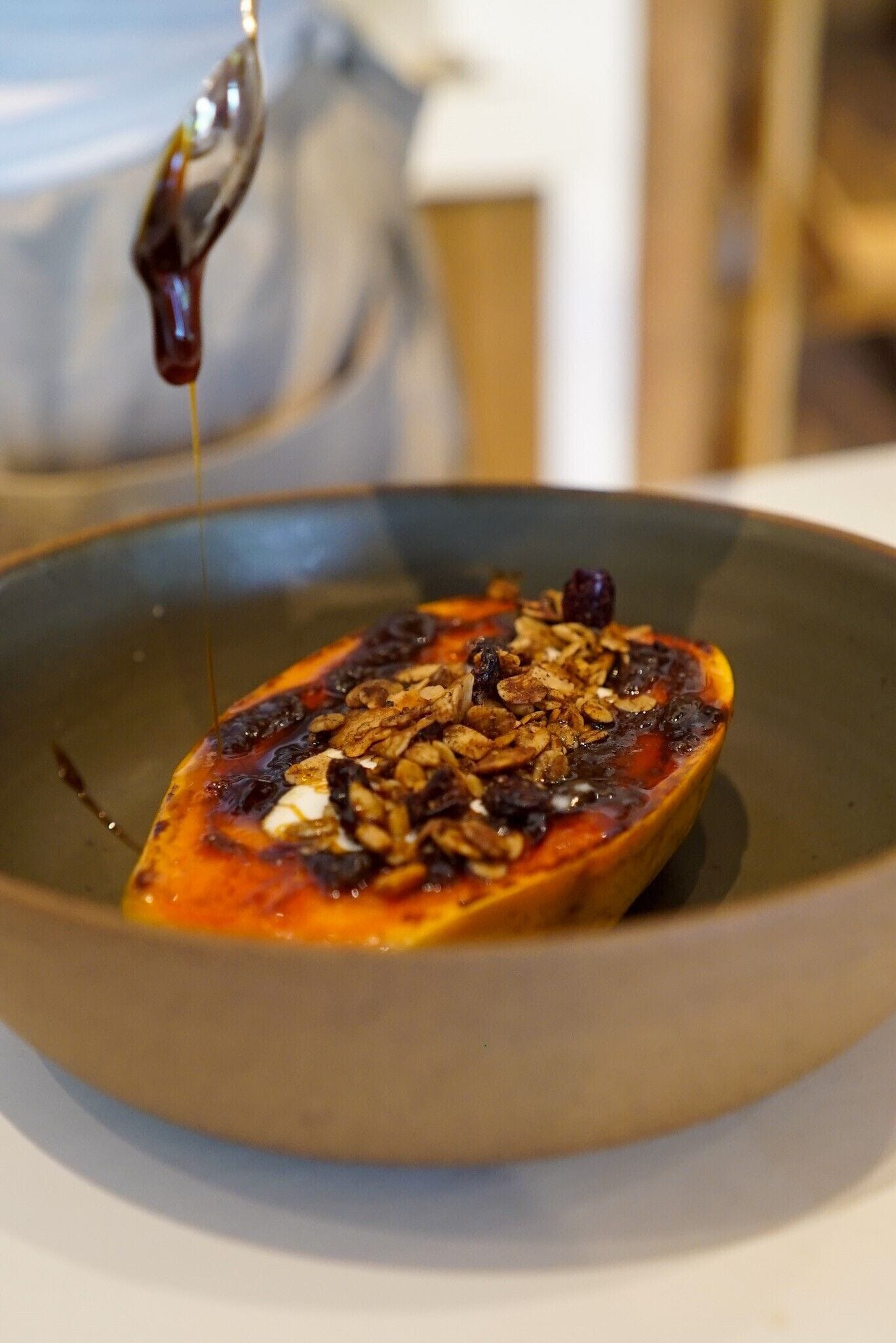 A bowl of food with a spoon pouring syrup over it.