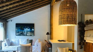 A cozy living area with a round table, wicker chairs, a sofa, and a hanging light fixture.