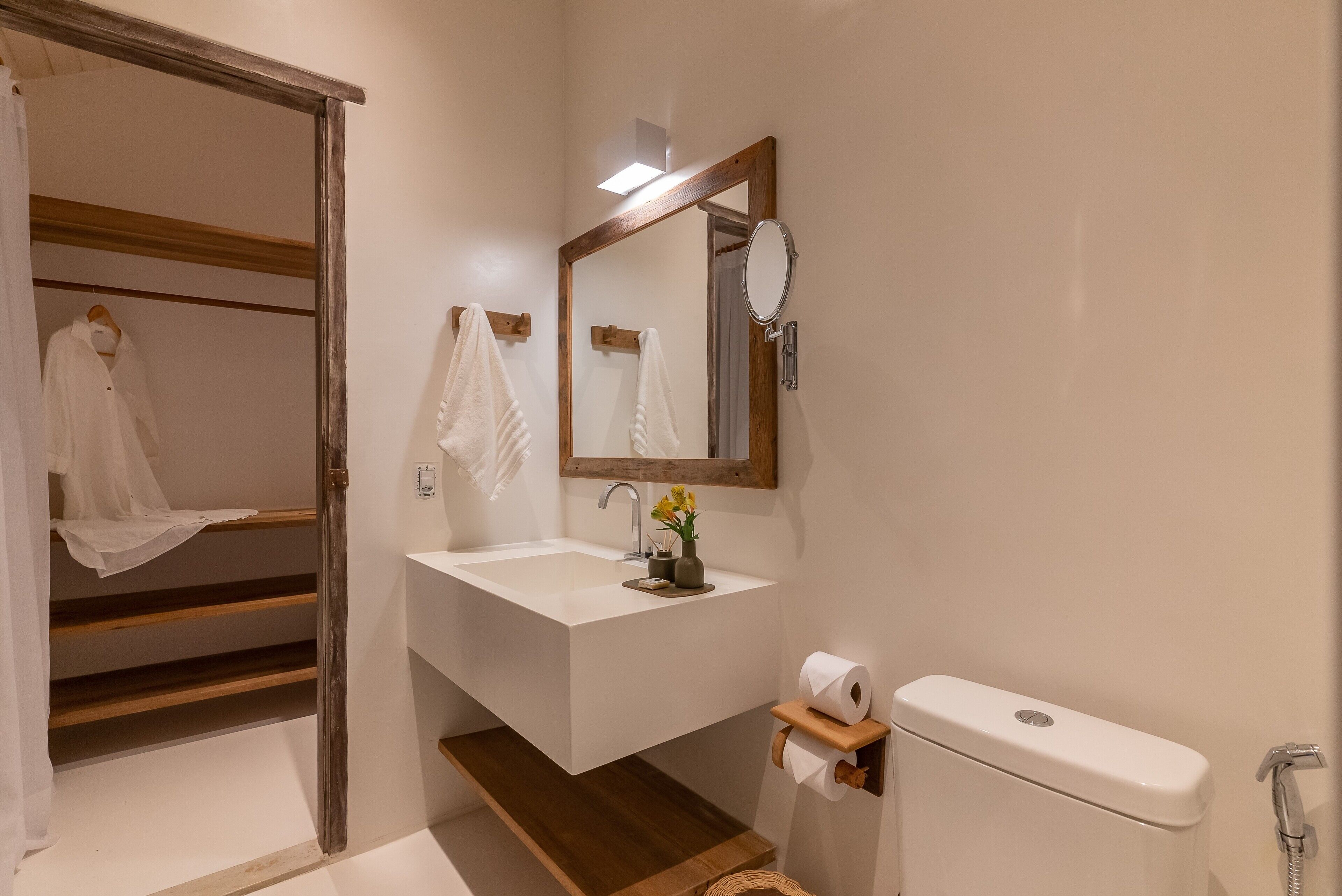 A bathroom with a wooden vanity, a mirror, a toilet, and a shower area.