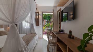 Un dormitorio con cama, mesita de noche, silla, televisión y vistas al jardín.