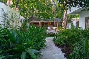 A pathway leading to a house with a covered porch and outdoor furniture.