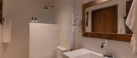 Un bagno moderno con lavandino bianco, mobile contenitore in legno, specchio e cabina doccia.