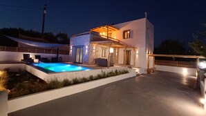 A modern house with a swimming pool, outdoor seating, and a covered patio area.