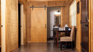 Un intérieur en bois avec une porte coulissante, une table avec des chaises et un miroir.