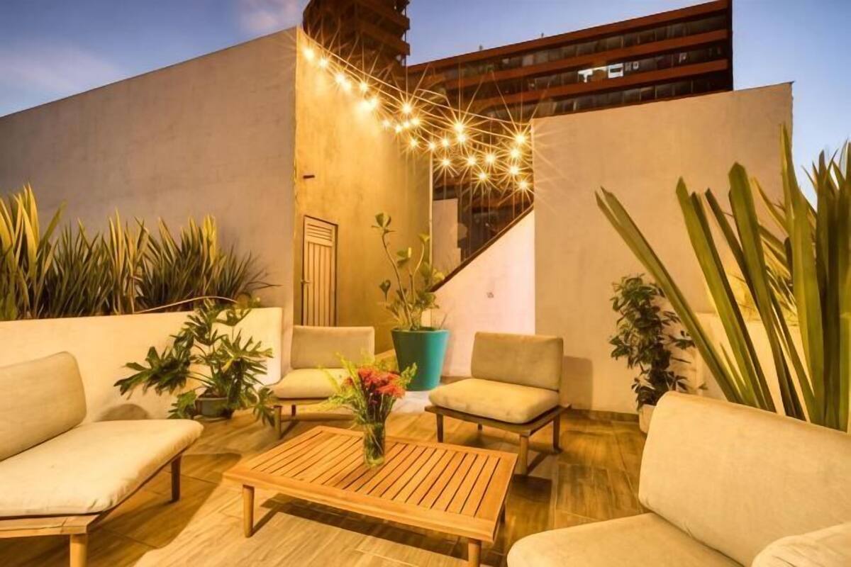 Eine Terrasse im Freien mit Sitzgelegenheiten, Pflanzen und Lichterketten.
