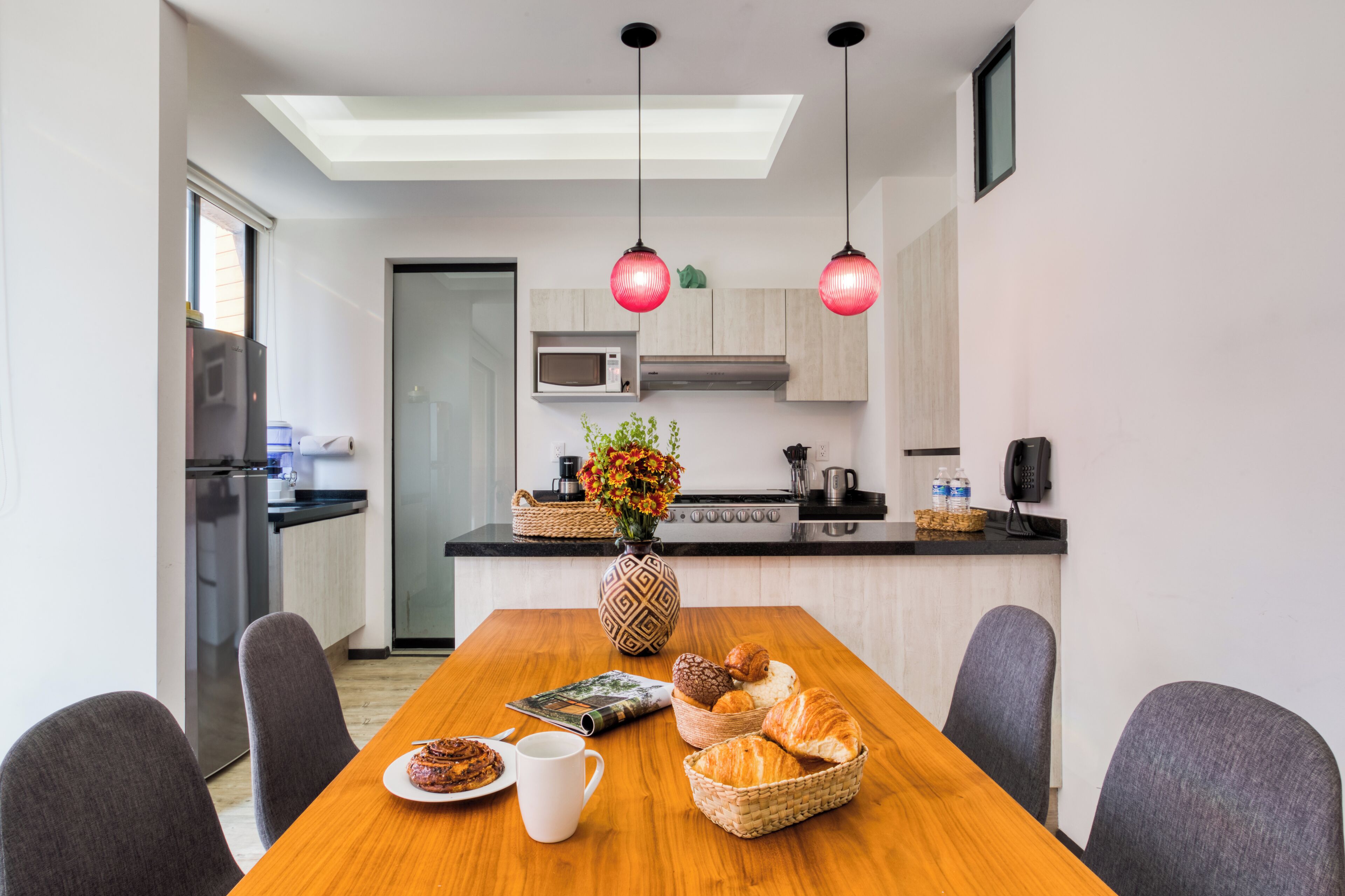 A modern kitchen with a dining table set for two, a microwave, and a coffee maker.