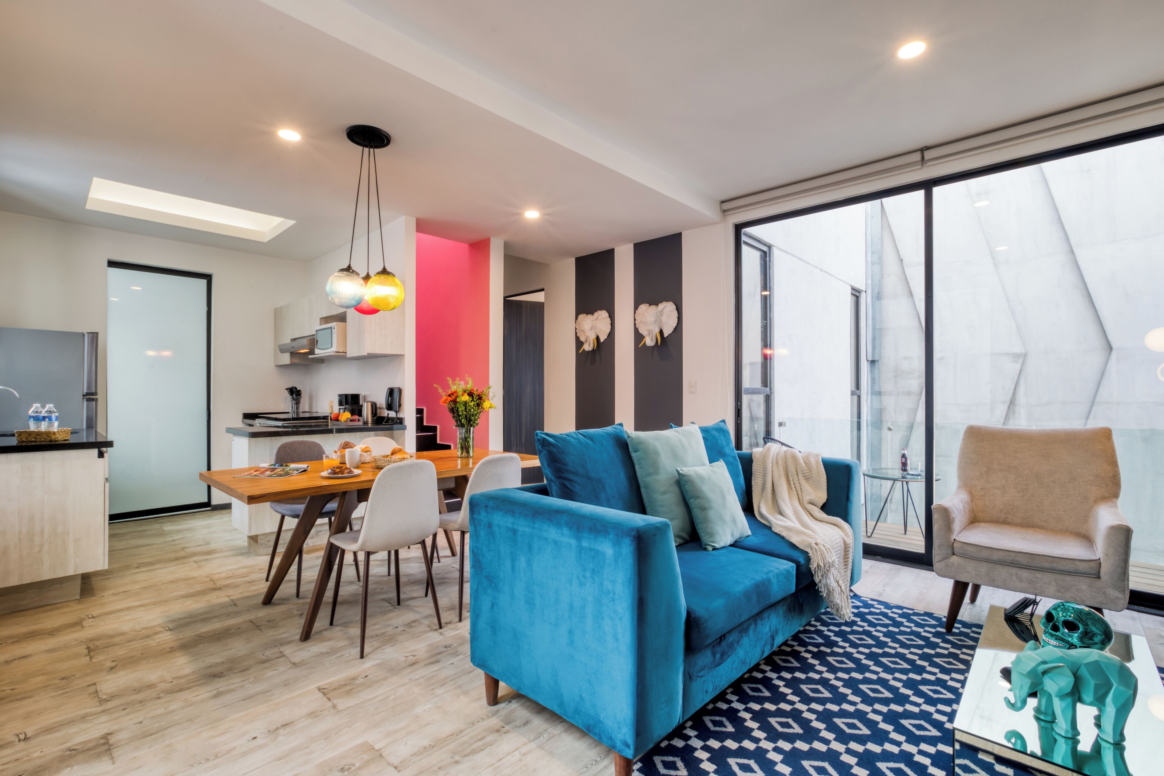 Un salon moderne avec un canapé bleu, un coin repas et une cuisine.