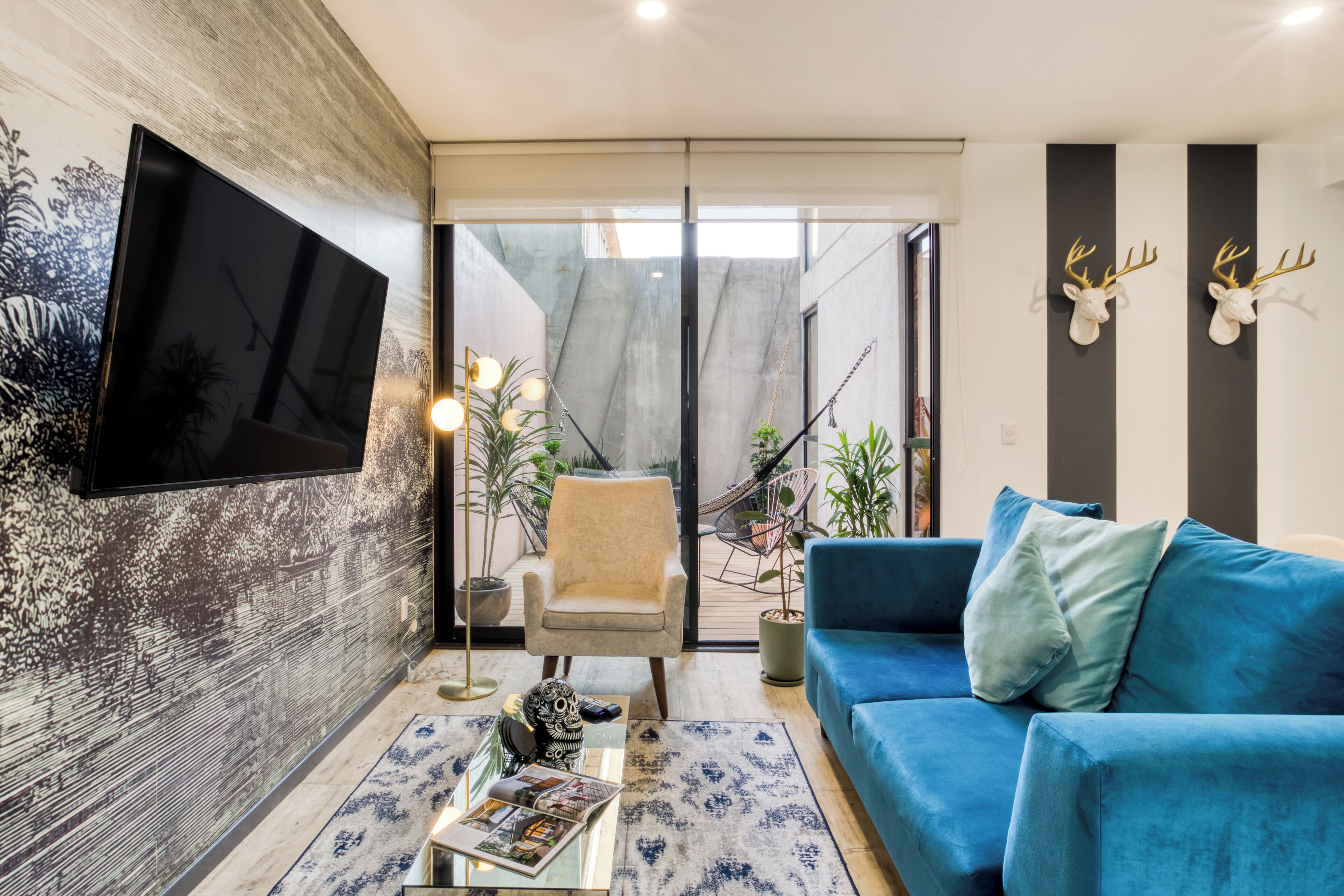 Una sala de estar moderna con un sofá azul, un televisor de pantalla plana montado en la pared y ciervos decorativos en la pared.
