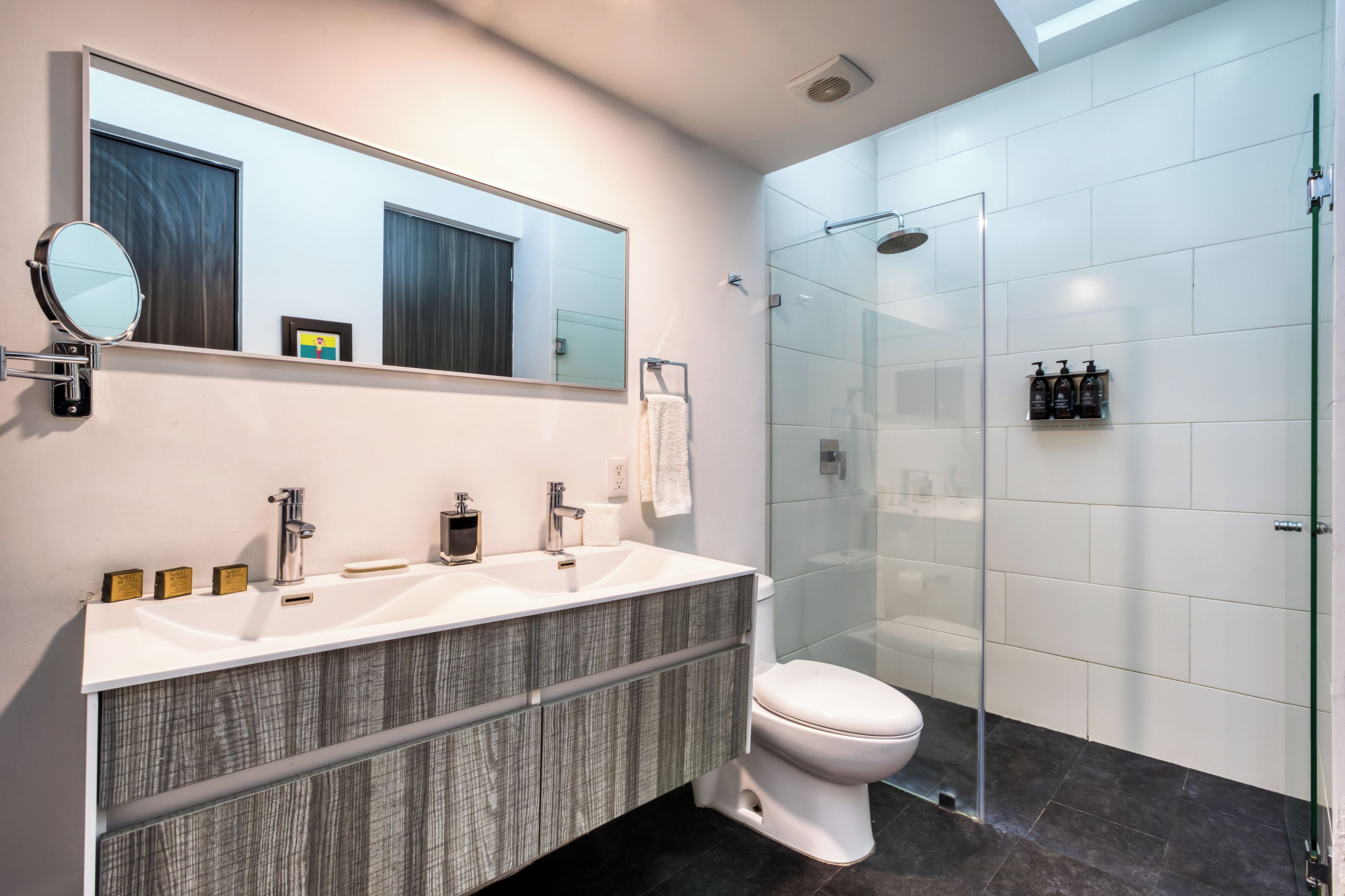 A modern bathroom with a glass-enclosed shower, a double sink vanity, and a large mirror.