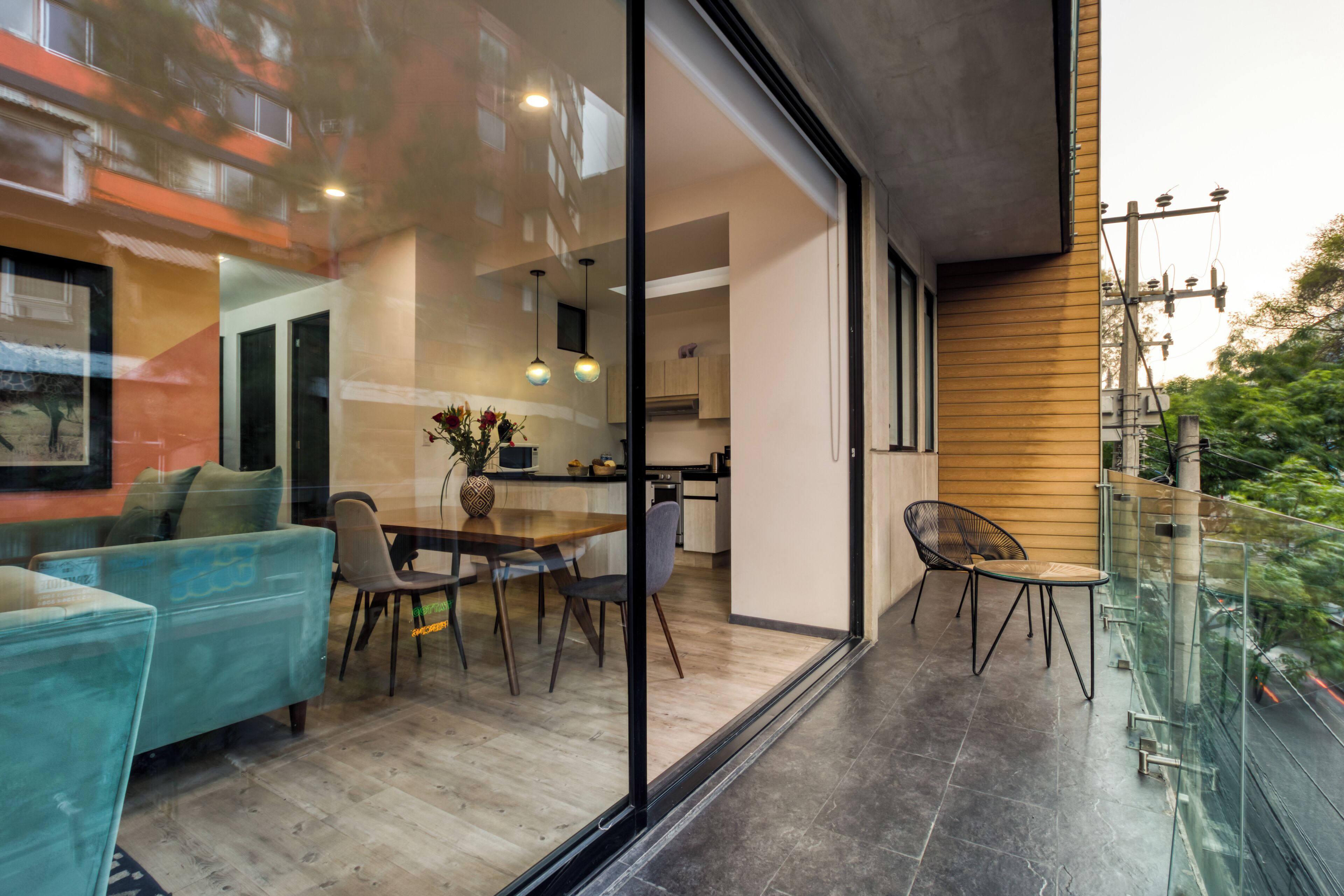 Een modern interieur met een eethoek, keuken en een balkon met glazen balustrade.