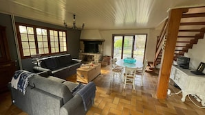 Amplia sala de estar con chimenea, comedor y escalera.