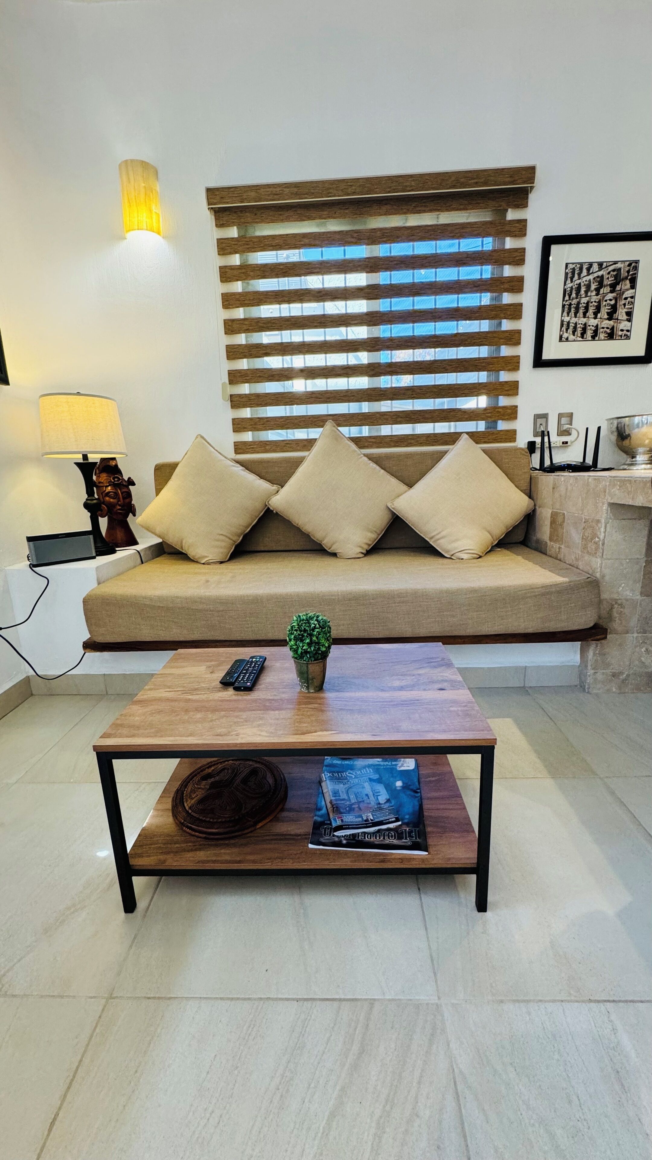 A living room with a sofa, a coffee table, a lamp, and a framed picture on the wall.