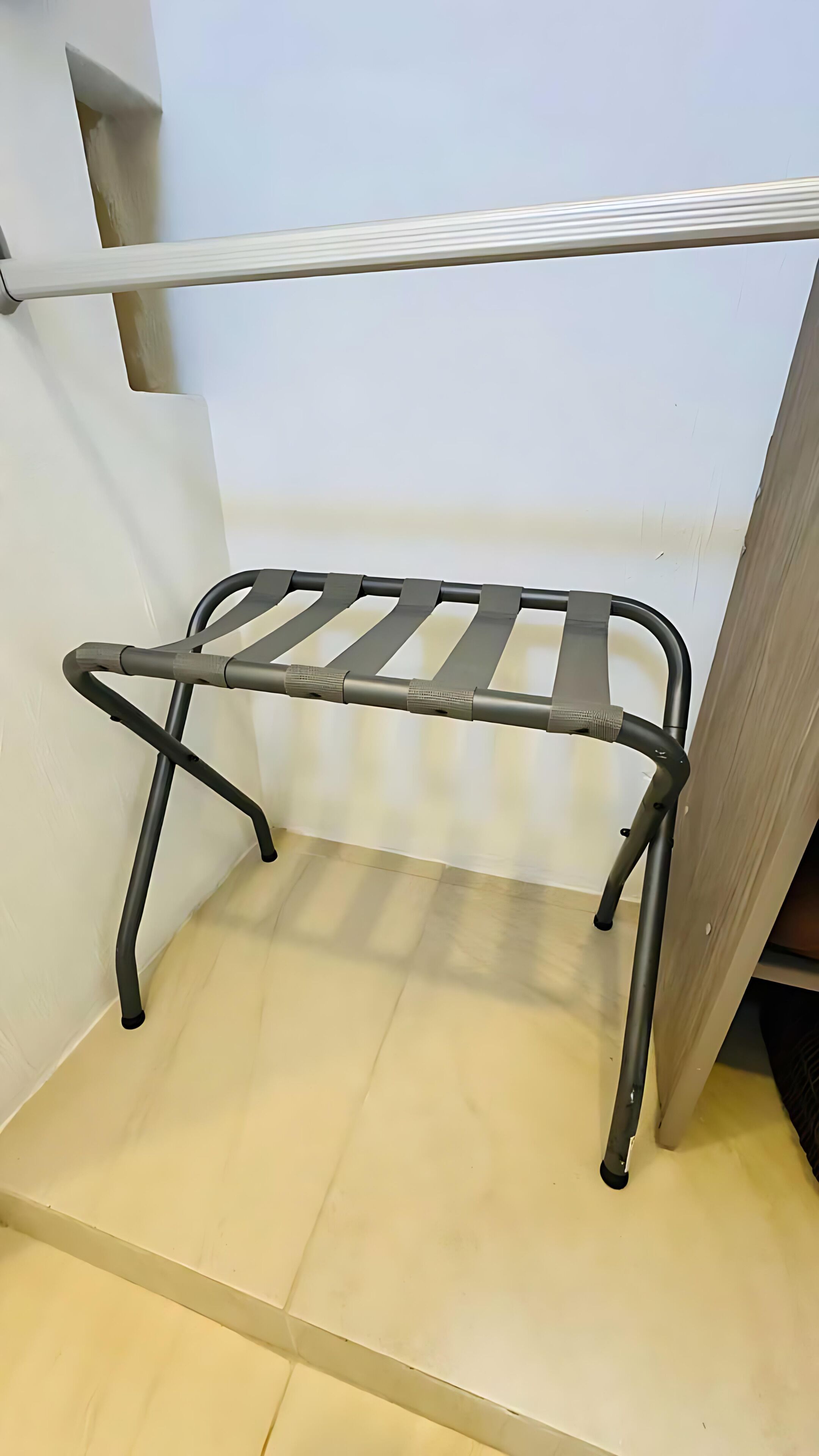 Un tendedero metálico en una habitación con pared blanca y puerta de madera.