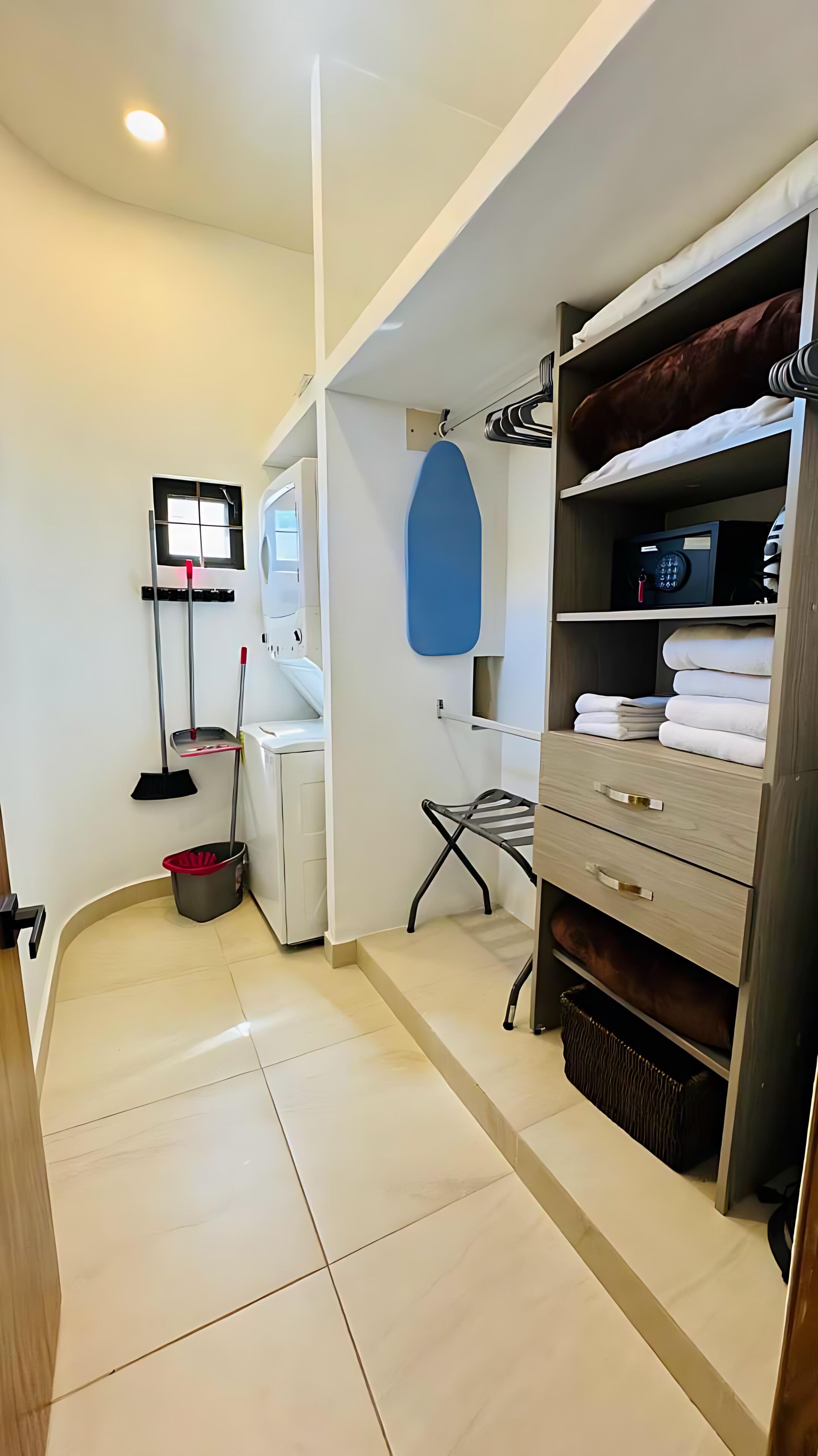 A clean, modern bathroom with a toilet, sink, and shower area. There is a towel rack and a drying rack.
