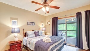 A bedroom with a bed, a nightstand, a lamp, a ceiling fan, and a window with curtains. - Cozy Mars Hill Farmhouse w/ Scenic Views (Mars Hill)
