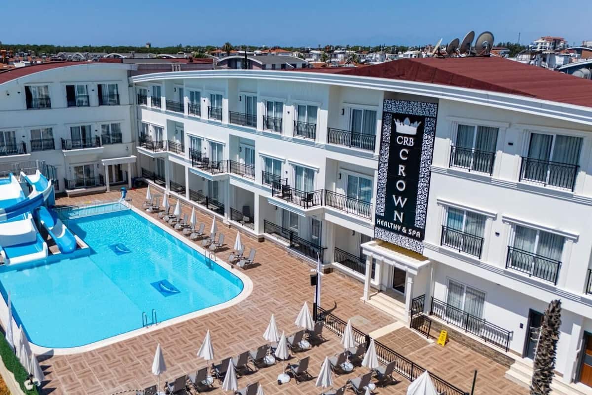 Ein Hotel mit einem großen Pool, mehreren Balkonen und einem Schild mit der Aufschrift "CRB CROWN HEALTHY & SPA".