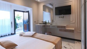 Ein modernes Hotelzimmer mit einem großen Bett, einem an der Wand montierten Fernseher und einem Badezimmer mit Spiegel und Waschbecken.