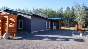 A single-story building with a gravel driveway and a wooden pergola. - Yukon Hot Springs Villa #31 (Whitehorse)
