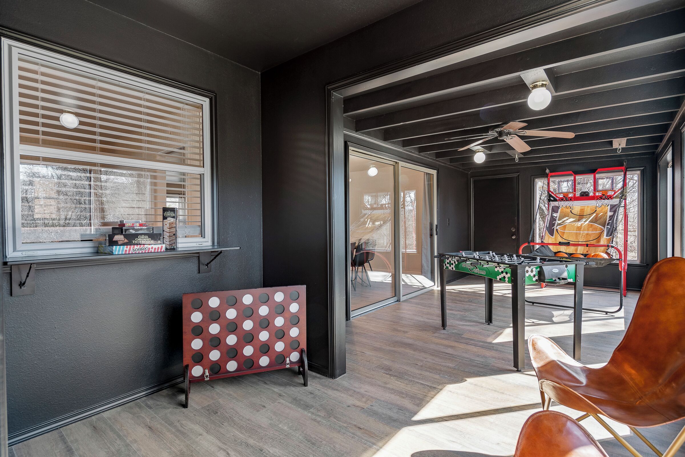 A modern room with a foosball table, a red and white board game, and a ceiling fan.