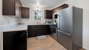 A modern kitchen with dark wooden cabinets, stainless steel appliances, and a white countertop. - GameRoom, Trail access seconds away, cozy! (Bella Vista)