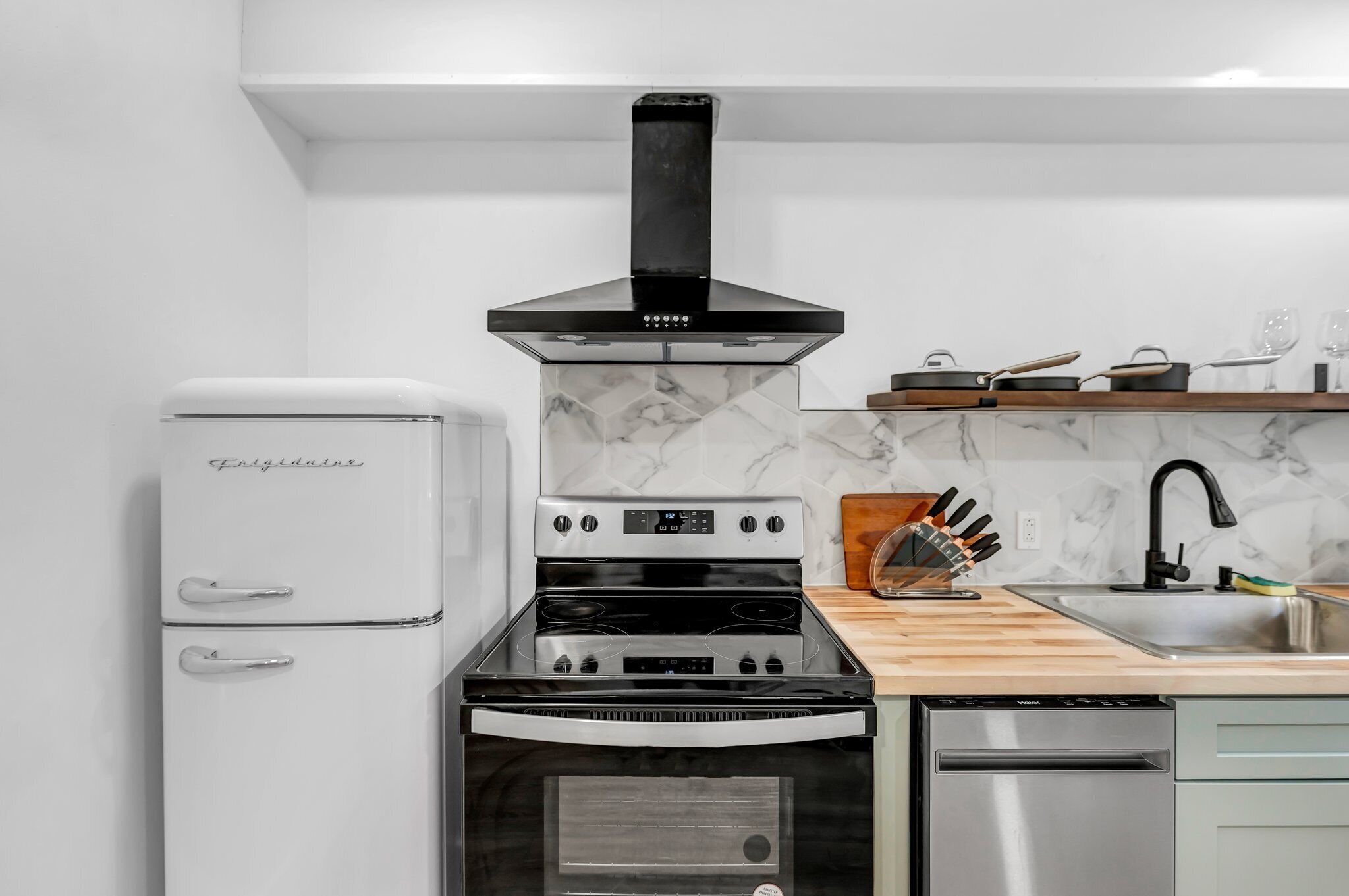 A modern kitchen with a white refrigerator, a black stove, and a dishwasher.
