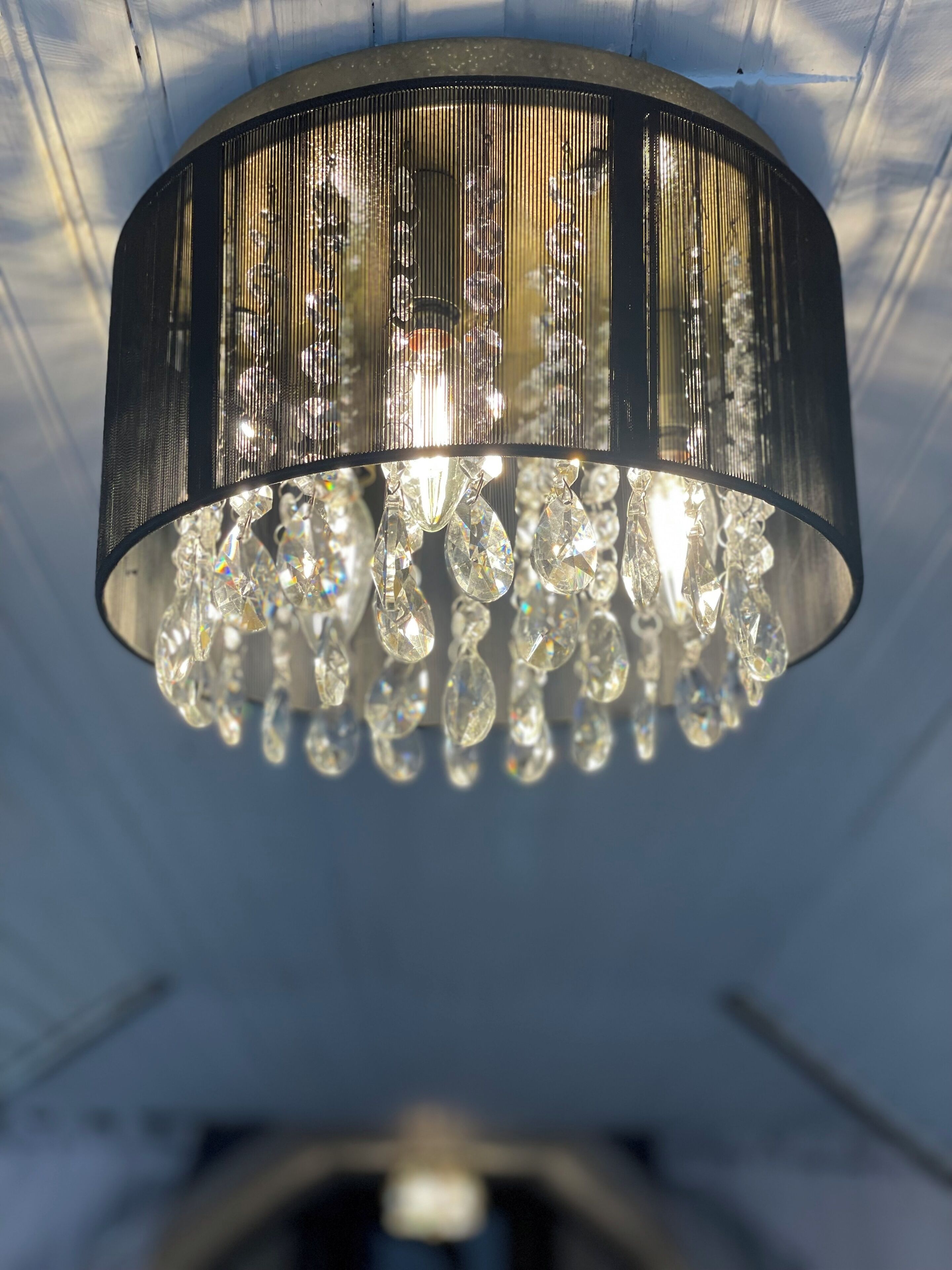 Un lampadario con numerosi elementi in cristallo sospeso da una struttura in metallo nero.