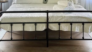 A bed with a metal frame, white bedding, and a floral-patterned headboard. - Historic Carriage House Suite (Mannington)