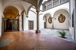 An interior courtyard with arched ceilings, a central column, and a potted plant.
