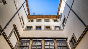 A courtyard with two arches and a central column, with a view of the sky through the arches. - YID Bargello luxury suite (Firenze)