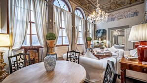 A luxurious room with a round wooden table, white sofas, and elegant chandeliers. - YID Bargello luxury suite (Firenze)