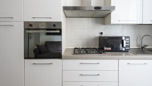 A modern kitchen with white cabinets, a gas stove, a microwave, and a built-in oven. - Cosy Vatican Apartment (Roma)