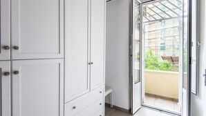 A room with a sliding glass door leading to a balcony, a white wardrobe, and a bench. - Cosy Vatican Apartment (Roma)